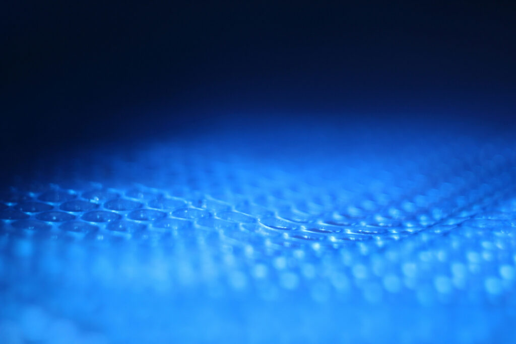 Gros plan macro de gouttes d'eau sur une surface texturée, éclairage bleu
