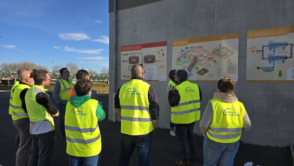 Groupe en visite devant un panneau pédagogique expliquant le fonctionnement de la station d'épuration
